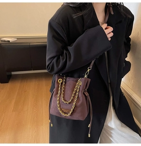 Détail d'un sac seau en daim avec chaîne dorée et marquage de mode en relief
