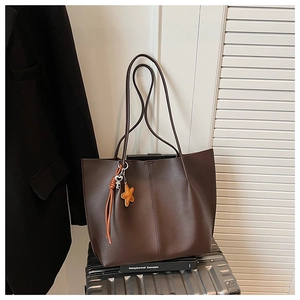 Detail view of coffee brown leather tote bag with elegant stitching and star keychain charm