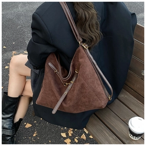 Detail of a large brown suede tote bag with adjustable strap in an autumn street setting