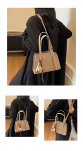 Detail of minimalist beige pillow bag with athletic baseball charm and textured finish