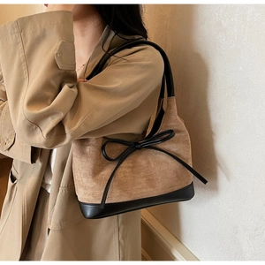 Détail du sac cabas en daim kaki avec contraste en cuir noir et nœud décoratif élégant