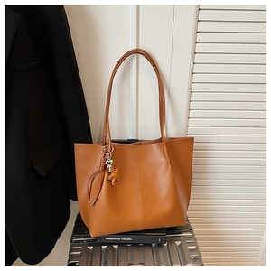 Detail view of brown faux leather tote bag with star charm on silver suitcase