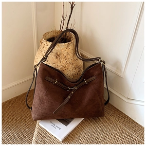Detailed side view of large dark brown suede tote bag with vintage metal buckle accent