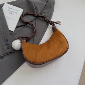 Detailed view of brown suede crescent bag with woven rope strap and white faux fur ball charm