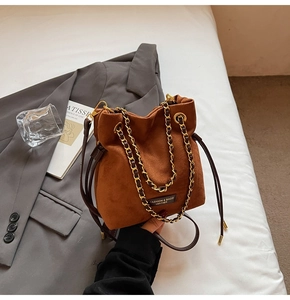 Détail du sac seau en daim caramel avec chaîne dorée et fermeture à cordon