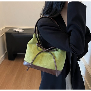 Détail du sac cabas en daim vert avec anses en cuir marron et nœud décoratif élégant