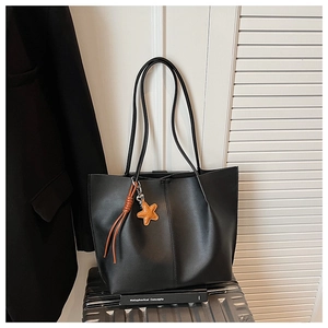Detail of a black tote bag with star pendant on a suitcase for office commuting
