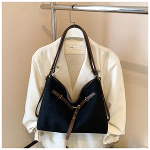 Close-up of black retro tote bag with brown leather straps and metal buckle detail