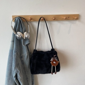 Détail du sac en fausse fourrure noire avec poupée en peluche et nœud léopard sur cintre