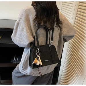 Detailed view of black shoulder bag with designer baseball charms and silver hardware