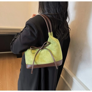 Détail de la texture en daim vert avocat et du nœud en cuir marron sur le sac cabas