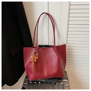 Detail view of deep red leather tote bag with star charm on silver suitcase