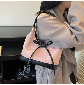 Détail du sac cabas en daim rose et similicuir noir avec décoration de nœud sur modèle