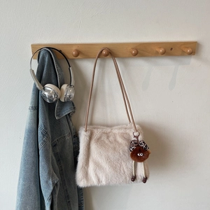 Détail du sac à épaule en fausse fourrure beige avec sangles brunes et pendentif peluche