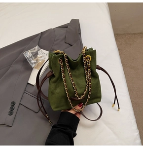 Détail du sac seau en daim vert avec cordon en cuir et bandoulière chaîne dorée