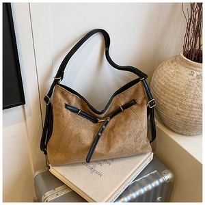 Detail of vintage brown suede tote bag with black leather straps on a silver suitcase