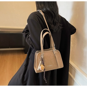 Chic beige PU leather shoulder bag featuring unique baseball pendant details on model