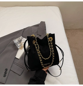 Détail du sac seau noir mat avec chaîne dorée et poignée en cuir réglable élégante