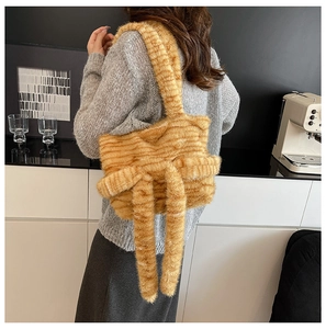 Detail of soft orange striped plush shoulder bag featuring decorative long cat tails