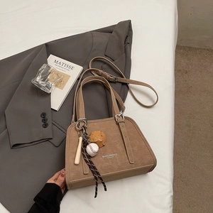 Close-up of khaki retro texture shoulder bag with unique baseball theme pendants and logo