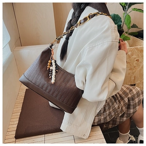 Details der gewebten braunen Hobo-Tasche mit goldener Kette und Holzperlen-Deko
