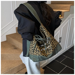 Detail of leopard print tote bag with green canvas base and decorative bow accent