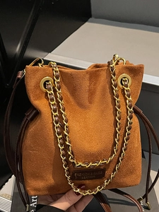 Sac seau en daim marron avec bandoulière chaîne dorée pour looks d'automne chic
