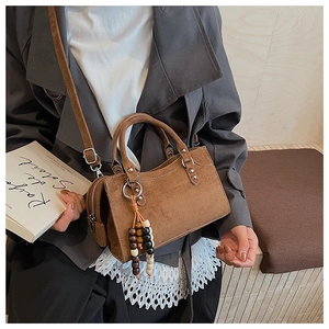 Brown suede textured bag with beaded tassel detail and shoulder strap shown on model