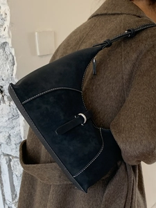 Chic black suede underarm bag with contrast stitching and silver buckle on model