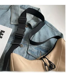 Detail of beige nylon crescent bag featuring adjustable black strap and dual zipper closure