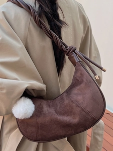 Vintage brown crescent shoulder bag with braided strap and plush ball charm on model