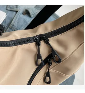 Detail of smooth black double-zipper and hexagonal puller on khaki tote bag