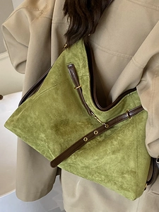Vintage green suede large tote bag with brown leather straps shown on a beige coat