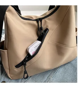 Close-up of khaki nylon tote bag featuring front zipper pocket and internal storage space