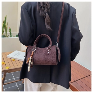 Detail view of coffee brown matte leather crossbody bag with wooden bead charm and dual handles