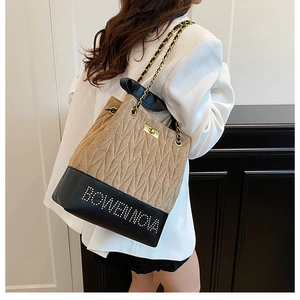 Detail of khaki quilted bucket bag with black leather base and elegant gold chain strap