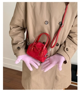 Detalle de mini bolso bandolera de ante rojo con lazo y correa de hombro delgada