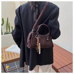 Detail of vintage coffee brown suede crossbody bag with decorative wooden beads charm