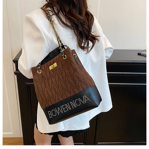 Close-up of brown quilted suede bucket bag with black leather base and gold chain strap