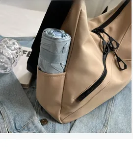 Detail of khaki crossbody bag featuring a practical side pocket for a folded umbrella