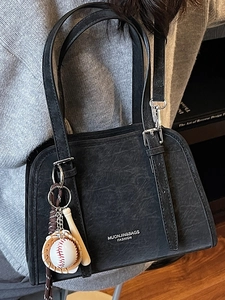 Glossy black shoulder bag with thin straps and a unique baseball charm accessory