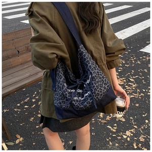 Macro shot of oversized leopard print tote bag with blue denim contrast and text detail