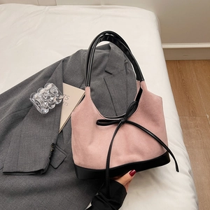 Détail du sac cabas en daim rose avec nœud en cuir noir et design hobo élégant