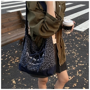 Detail of leopard print denim tote bag with creme de la creme text on vintage canvas