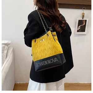 Detail of yellow quilted bucket bag with chain strap and Bowen Nova metal logo