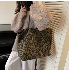 Close-up of leopard print canvas tote bag with black straps and metal badge detail