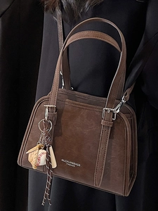 Dark brown matte shoulder bag with baseball charm and adjustable strap for women