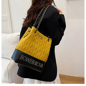 Detail view of quilted yellow and black chain bag with rhinestone rivet accents