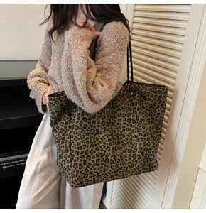 Detail shot of leopard print tote bag with black handles on a model in a warm room
