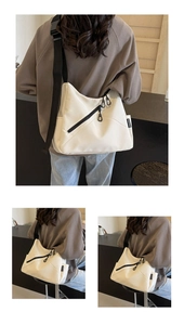 Detail of off-white crossbody bag featuring black diagonal zippers and wide strap